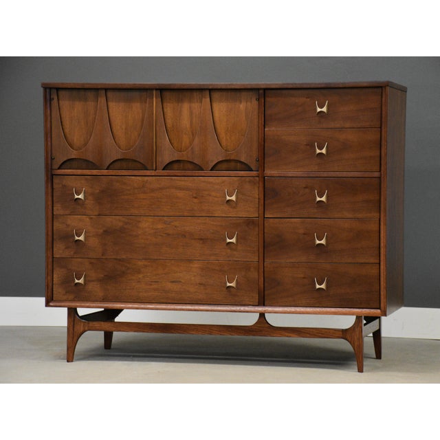 A mid century modern walnut eight drawer dresser credenza with swooping walnut and brass arch details made by Broyhill...