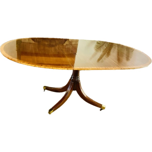 Elevate your dining space with this elegant Regency-style mahogany table. It features a stunning book-matched flame...