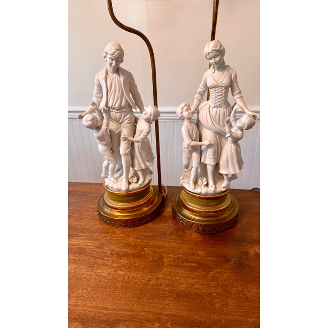This is a pair of large vintage table lamps featuring intricate figural sculptures made of white Parian bisque porcelain....