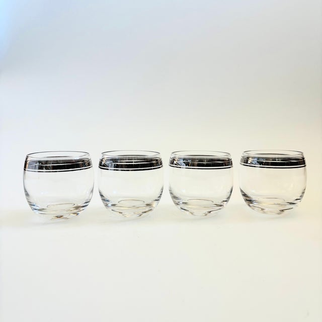 A set of 4 mid century roly poly cocktail glasses. Each glass is decorated with lines of silver along the top in the...