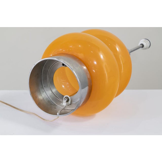 Stainless steel and orange glass table lamp. Two light points, one upper under the screen and another inside the glass...