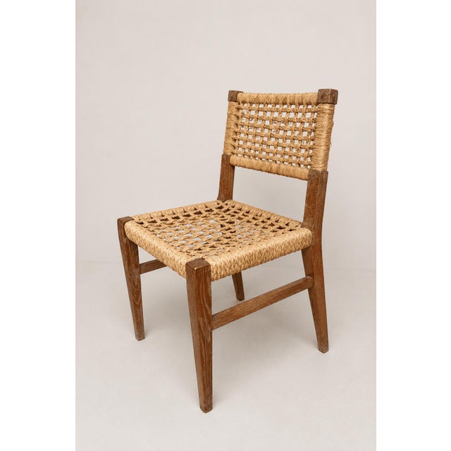 A pair of mid-century French side chairs attributed to Adrien Audoux and Frida Minet, combining solid oak frames with...