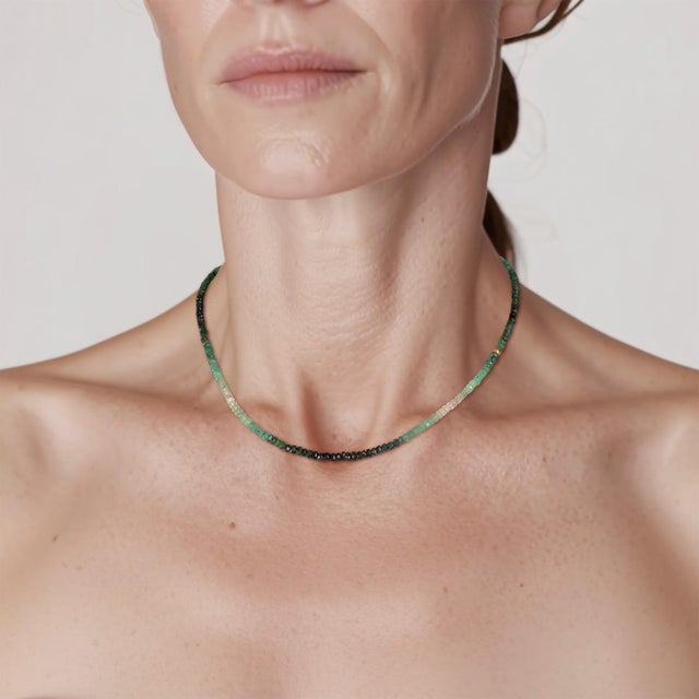 Emerald, graduated from deep green through pale mint to nearly clear. One 18K gold bead marks the transition, nothing...