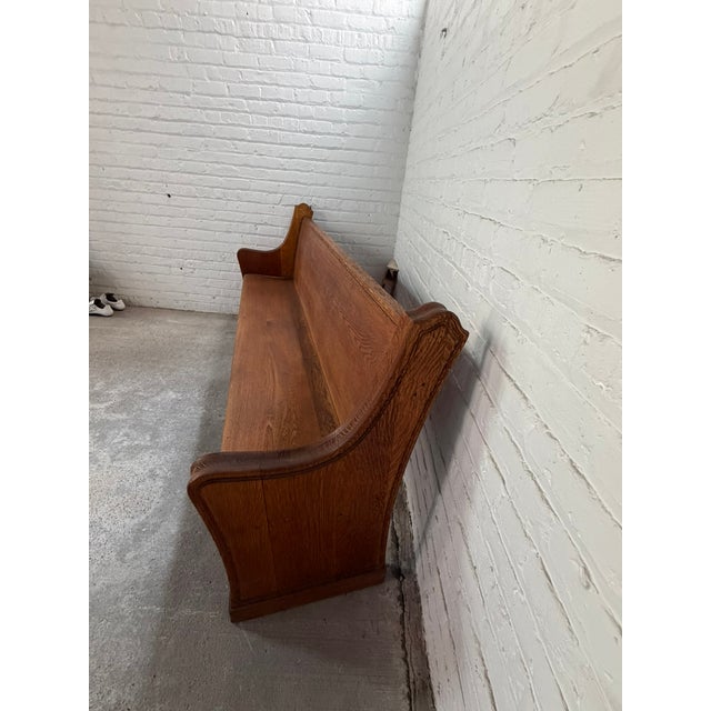 This beautiful antique church pew features a long, high‑back silhouette with sculptural curved end panels and warm,...