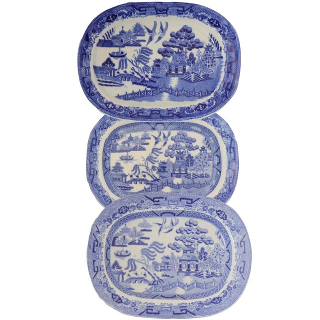 This set of three mixed antique blue-and-white English Willow pattern platters depict the classic Willow pattern, inspired...