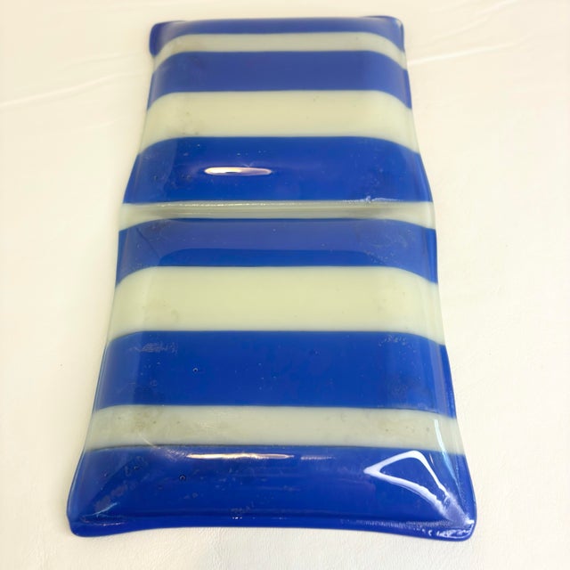 This fused glass rectangular tray features a vibrant blue, green, and white striped swirl pattern with a wavy, undulating...
