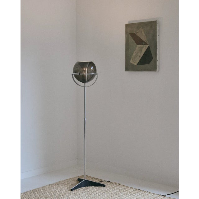 Smoked glass and chrome orb floor lamp by Frank Ligtelijn for RAAK with a fixed globe, 1960s. This piece has been newly re...