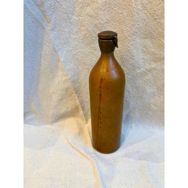 The bottle features a warm, naturally aged patina and a concave hand-formed base typical of 19th-century copperwork. The...