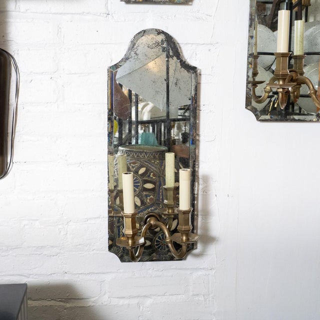 Beveled mirror and cast brass two-arm sconces. Sold individually.