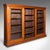 This is a large antique glazed bookcase. An English, grand walnut display cabinet with sliding doors, dating to the late...