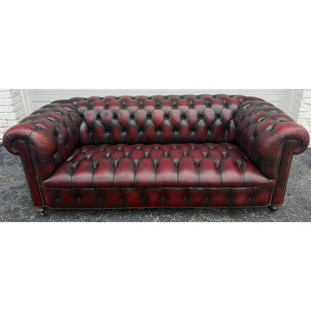 Pair of English Chesterfield Sofas in Burnished Burgundy Leather England, Circa 1950s A handsome and substantial pair of...