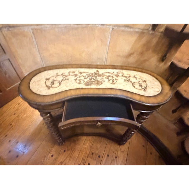 This Maitland-Smith–inspired kidney-shaped console table features a decorative faux tile top that adds texture and visual...