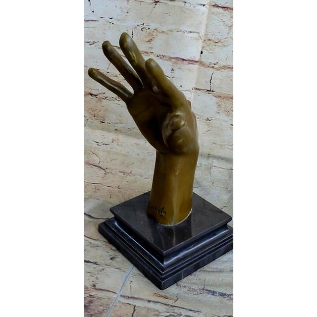A dramatic solid bronze surrealist hand sculpture, signed by the artist and mounted on a polished black marble base. This...