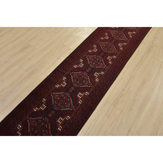 An authentic vintage Baloch tribal runner hand-knotted with fine wool and natural dyes. This nomadic oriental rug features...
