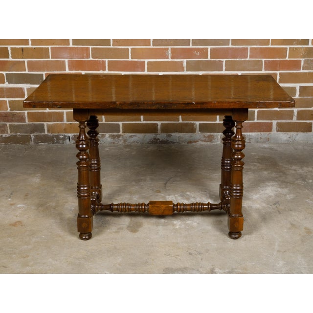 An Italian Baroque style walnut side table from circa 1800 with spool legs, H-Form cross stretcher and bun feet. This...