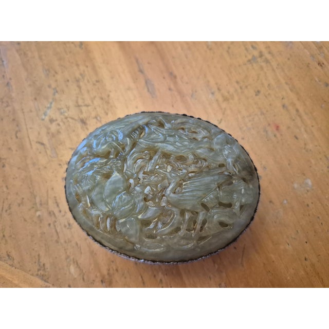 This vintage trinket box features a lid crafted from natural jade, carved with detailed floral and stork motifs in a...
