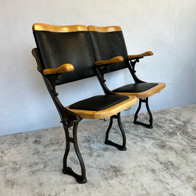 Pair of cinema seats featuring cast iron frames, bentwood construction, and folding mechanism with original hat stows...