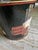 A colorful decoupage waste can bearing the label of Workman Partners, New York. It appears to be an old bucket with a hole...