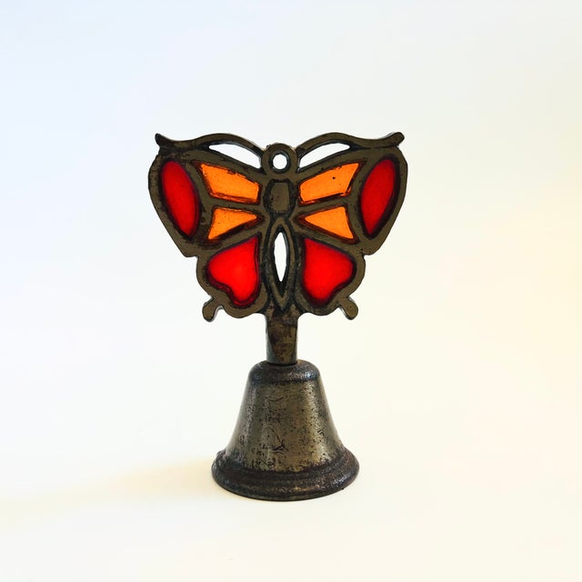 A vintage brass bell with a stained glass butterfly handle. Measures 3.25"W x 2"D x 4.5"H