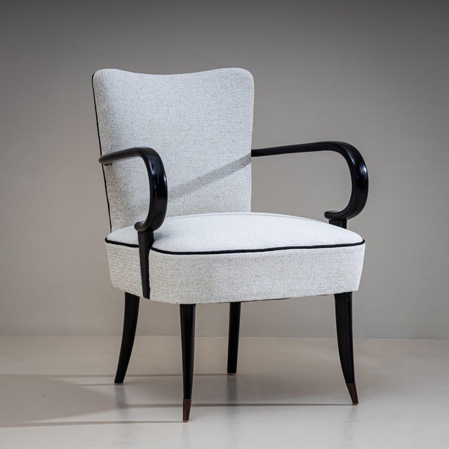 Pair of armchairs with rounded, ebonized armrests and upholstered seats and backrests. The chairs have been newly...