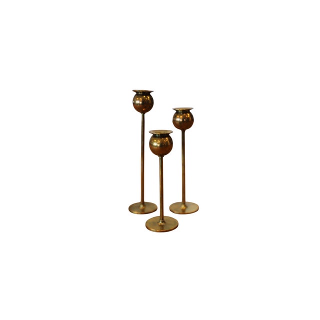 Three elegant brass candlesticks, designed by Pierre Forssell for Skultuna. Narrow stems carry rounded candle holders with...