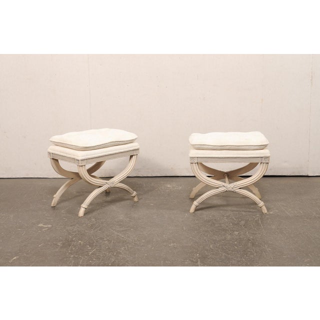 A French pair of reeded wood curule stools, with upholstered seats, from the mid 20th century. These vintage stools from...