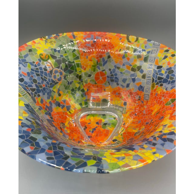 A striking vintage art glass bowl featuring a vibrant mosaic-inspired design in rich shades of cobalt blue, orange,...