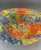 A striking vintage art glass bowl featuring a vibrant mosaic-inspired design in rich shades of cobalt blue, orange,...