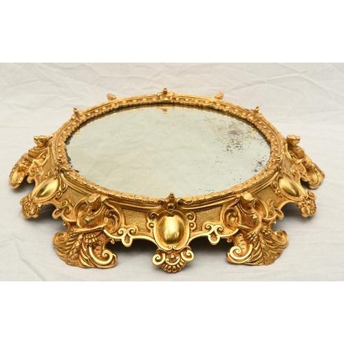 A striking French oromolu circular mirrored plateau of highly decorative form. The round bevelled mirror plate is set...