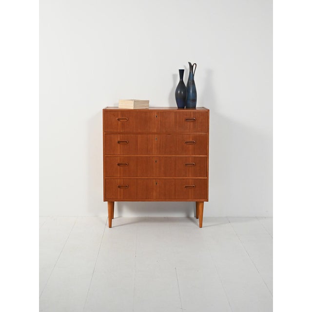 Teak chest of drawers with four drawers and recessed handles, a simple structure on tapered turned legs. Elegant...