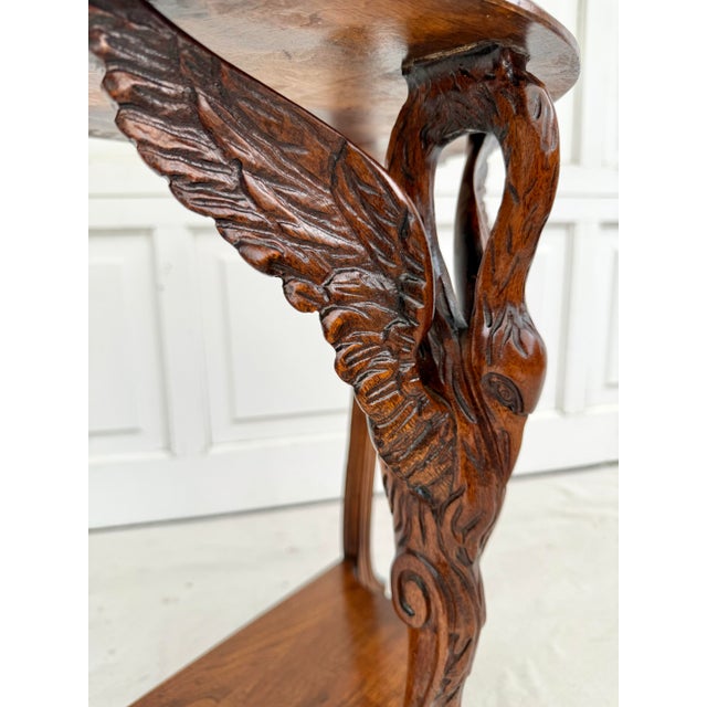 This striking early 20th century, likely 1920-30s, carved wood demi-lune table features an extraordinary sculptural swan...