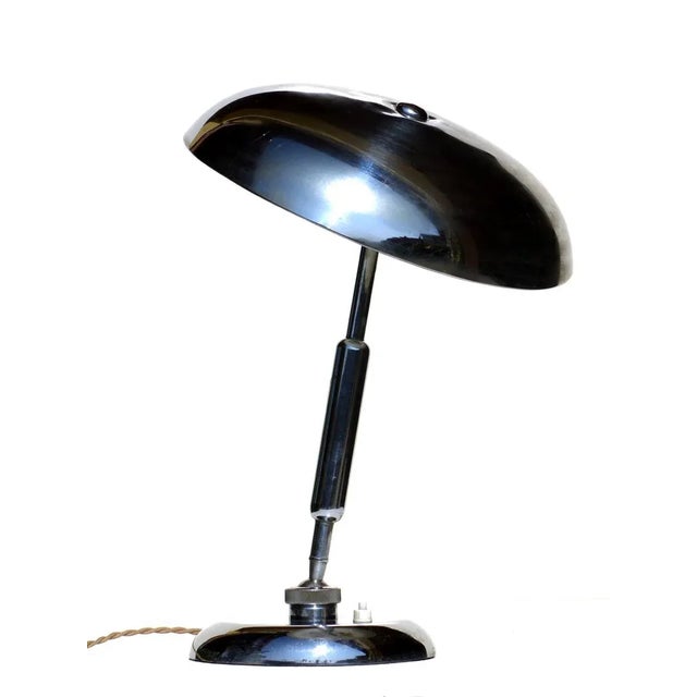 This table lamp in nickel-plated brass features an adjustable shade. European Plug (up to 250V).The wiring of this item...