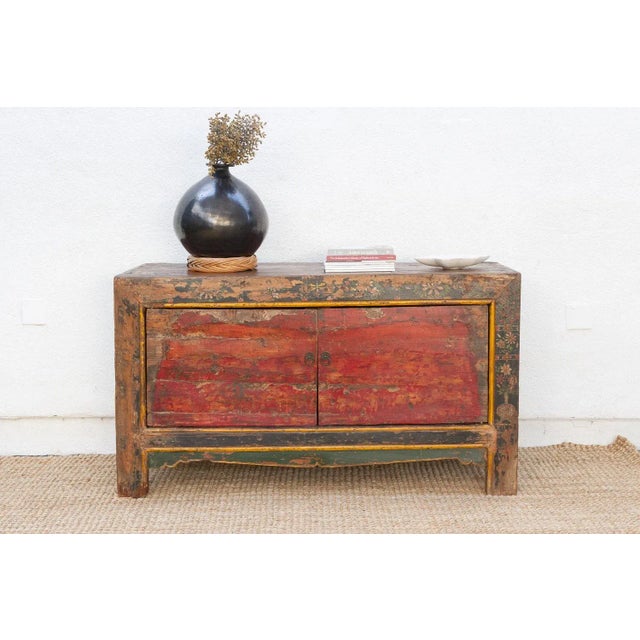 This striking antique cabinet is a vibrant piece of history, its surface a masterful tapestry of layered colors and worn...