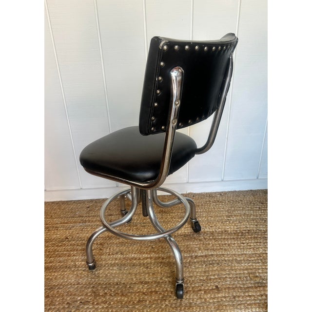 A striking blend of mid-century industrial and classic American style, this vintage swivel stool features a gleaming...