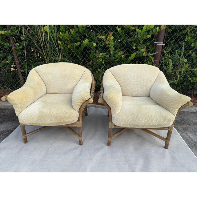 A beautiful pair of McGuire lounge chairs featuring sculptural rattan frames, gracefully curved arms, wrapped joints, and...