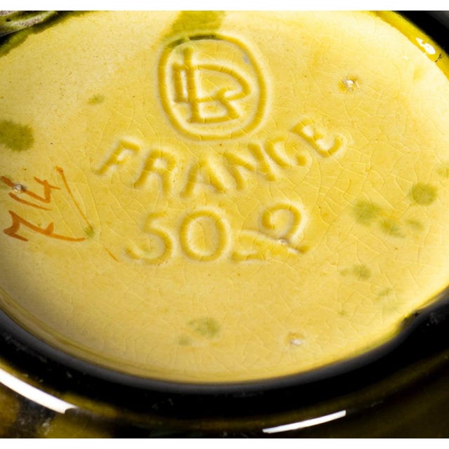 An art nouveau pair of faience vases in green ceramic with floral barbotine reliefs. the interiors are finished in a...