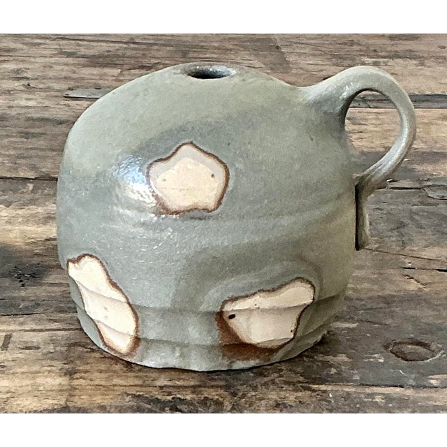 This charming studio pottery bud vase is a masterful example of organic modernism, featuring a squat, globe-like form...