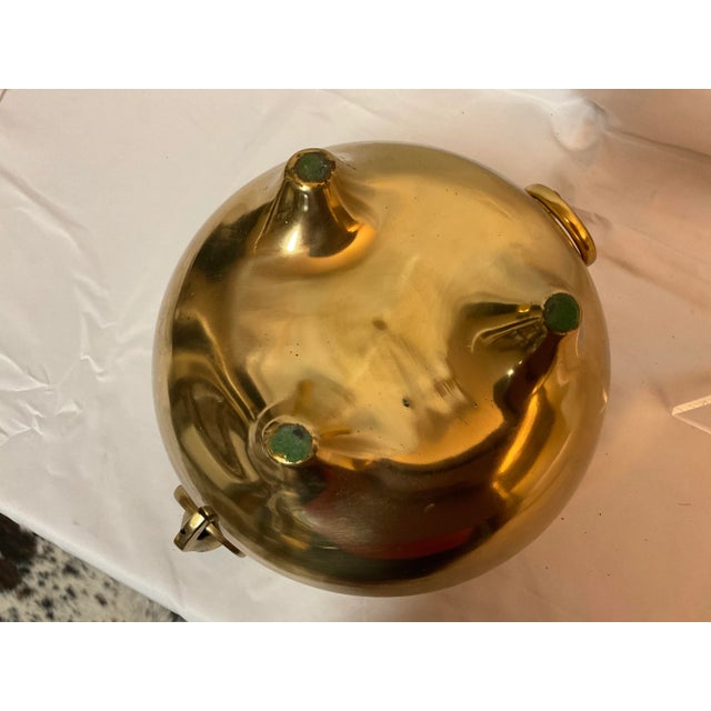 This is a heavy brass footed cauldron with beautiful patina and gnome-like faces that hold the two handles on either side....
