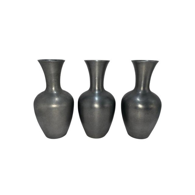 A refined and minimalist set of three pewter vases designed by Schreuder & Olsson, Sweden. These elegant vessels showcase...
