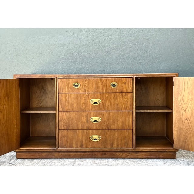 This vintage Drexel Campaign sideboard combines a warm wood finish with brass hardware and a clear, balanced silhouette....