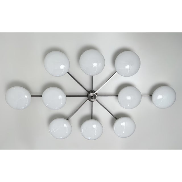 Italian midcentury flush mount with ten glossy white Murano glass shades mounted on solid brass frame in satin black...