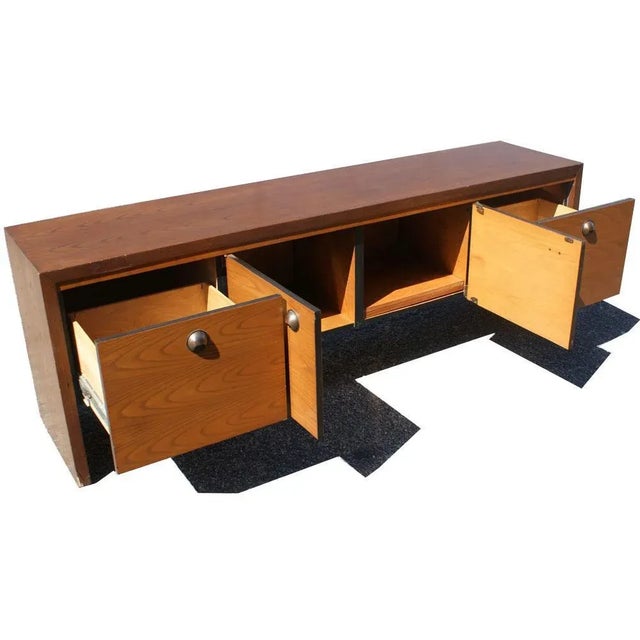 A mid century modern credenza made by Dunbar. Nicely figured continuous walnut graining on front doors and brass pulls.