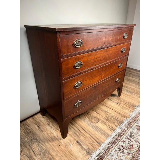 An exceptional and increasingly rare Federal period cherry chest of drawers bearing the original printed cabinetmaker’s...