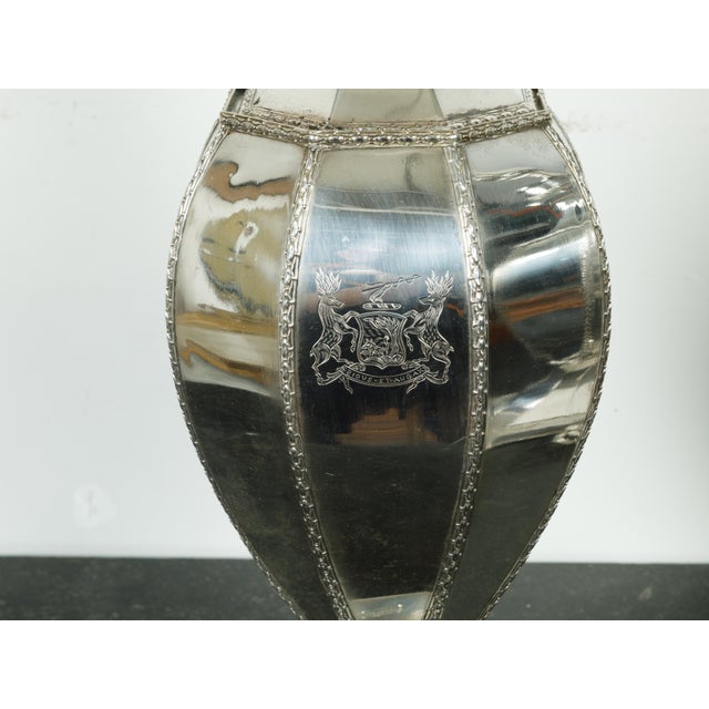A pair of silver plated table lamps from the mid 20th century, with Bious-et-Augax armorial crest. Created in England...