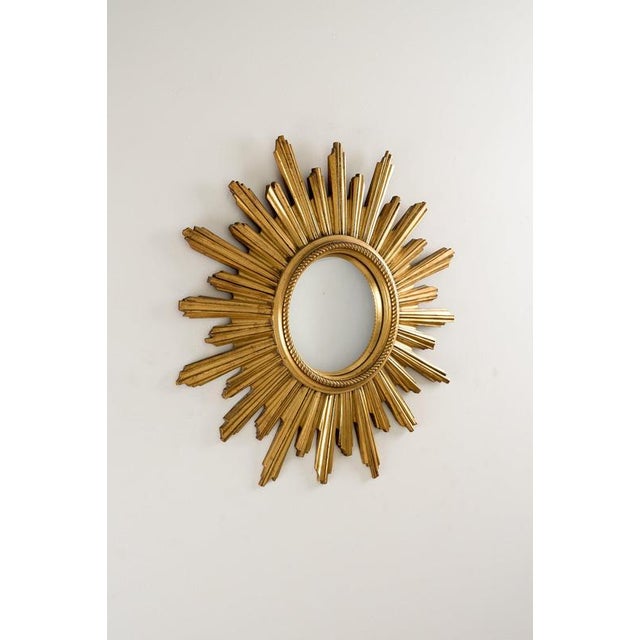 This intage wall mirror is a classic example of mid-century modern and hollywood regency design, produced by the belgian...