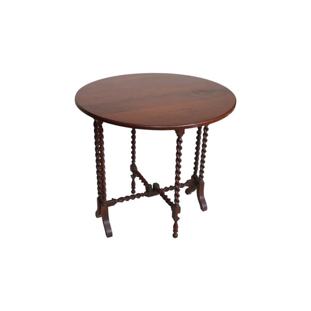 An English Edwardian period gate leg table made of oak. The round tabletop consists of a narrow center panel with two drop...