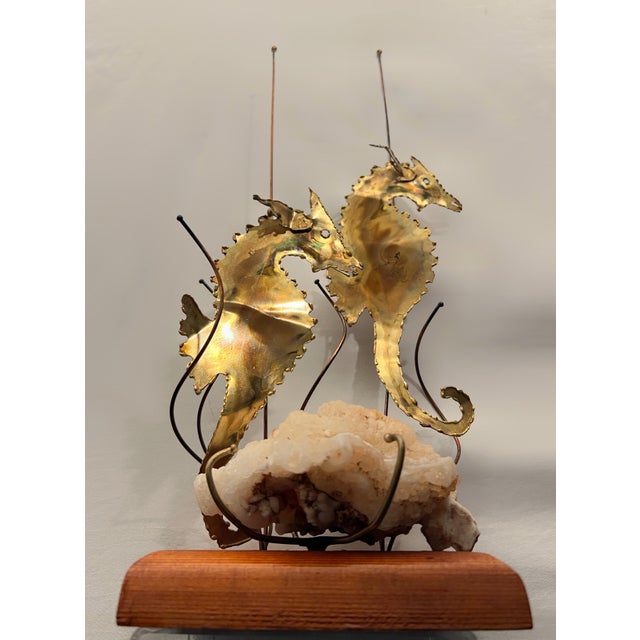 A striking handcrafted brass seahorse sculpture mounted on a natural quartz crystal and solid teak base, retaining its...