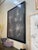 Abstract contemporary artwork with white splatter detailing over a dark ground, framed in a clean black frame. Subtle...
