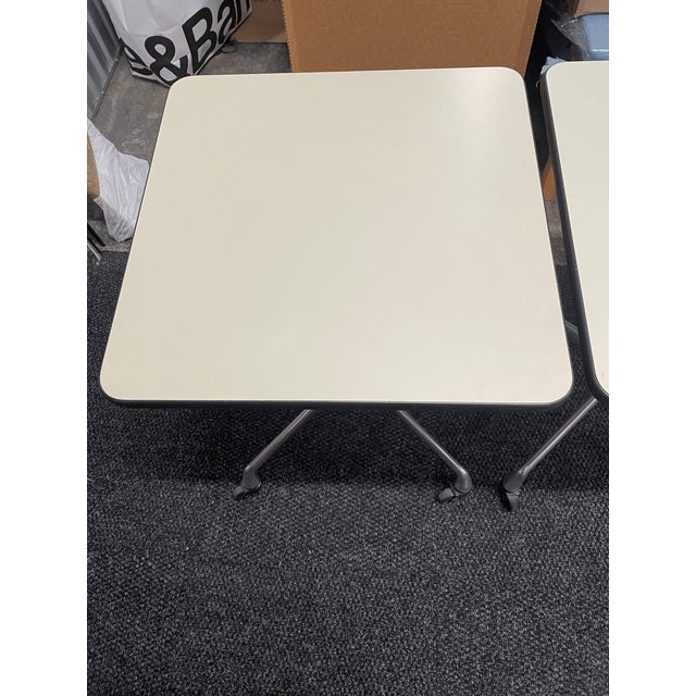 Herman Miller pair of mid-century side tables by Charles and Ray Eames with metal base on casters and white laminated top..