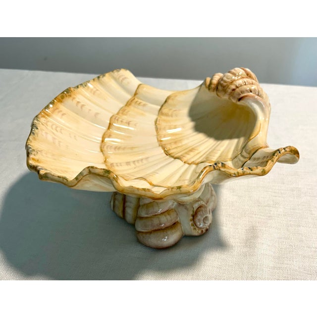 A sculptural Italian ceramic centerpiece in the form of a Triton shell, raised on an elaborate pedestal base. Richly...